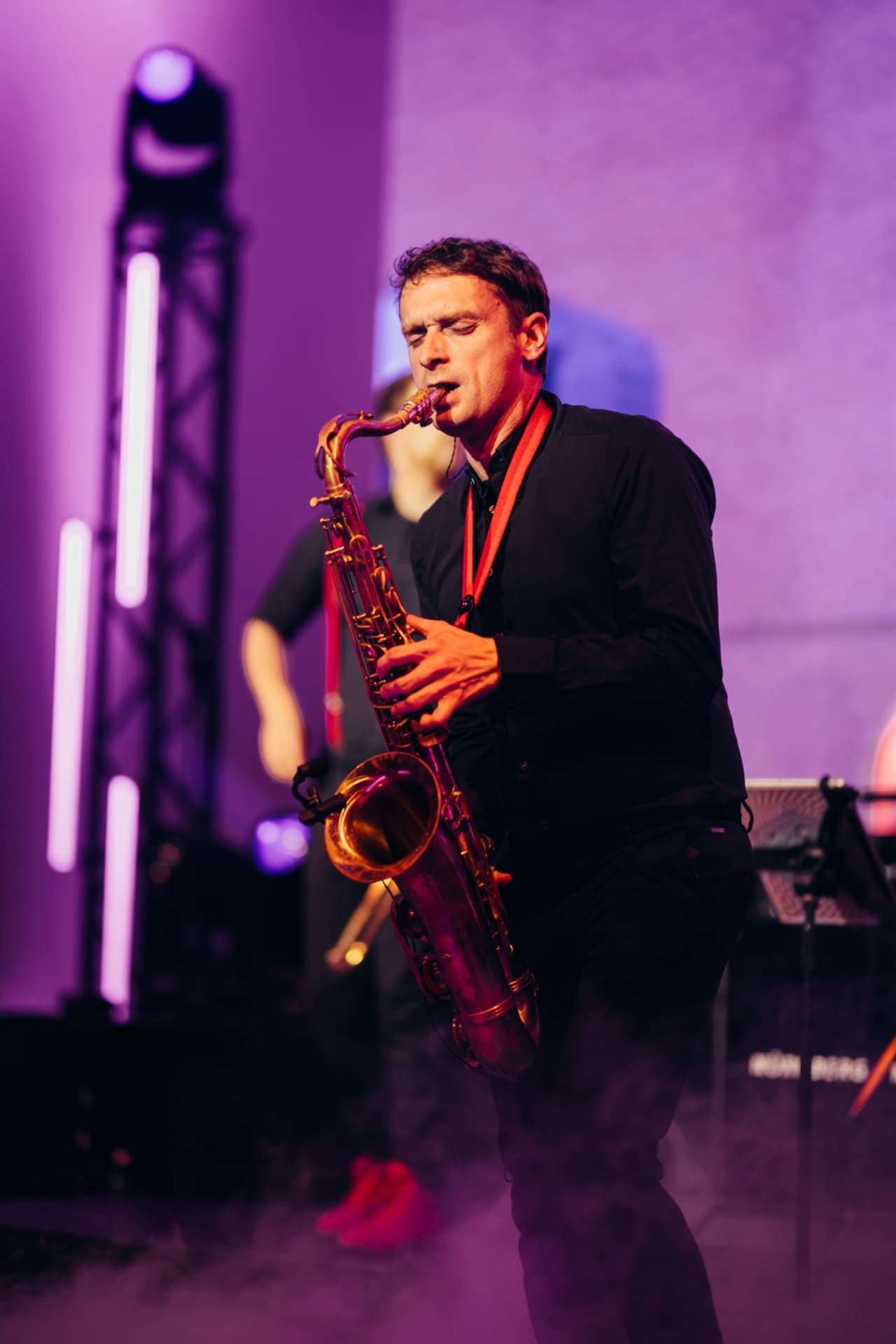 Saxophonist in lila Licht und Bühnennebel