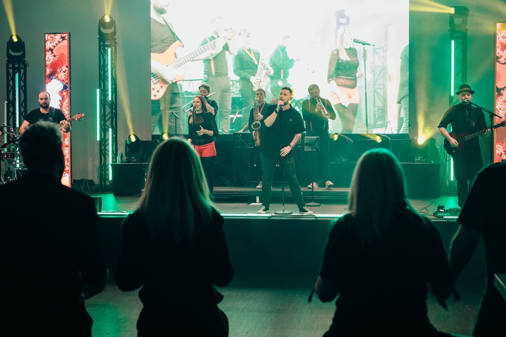 Band aus der Publikumsperspektive mit grüner Beleuchtung und Silhouetten