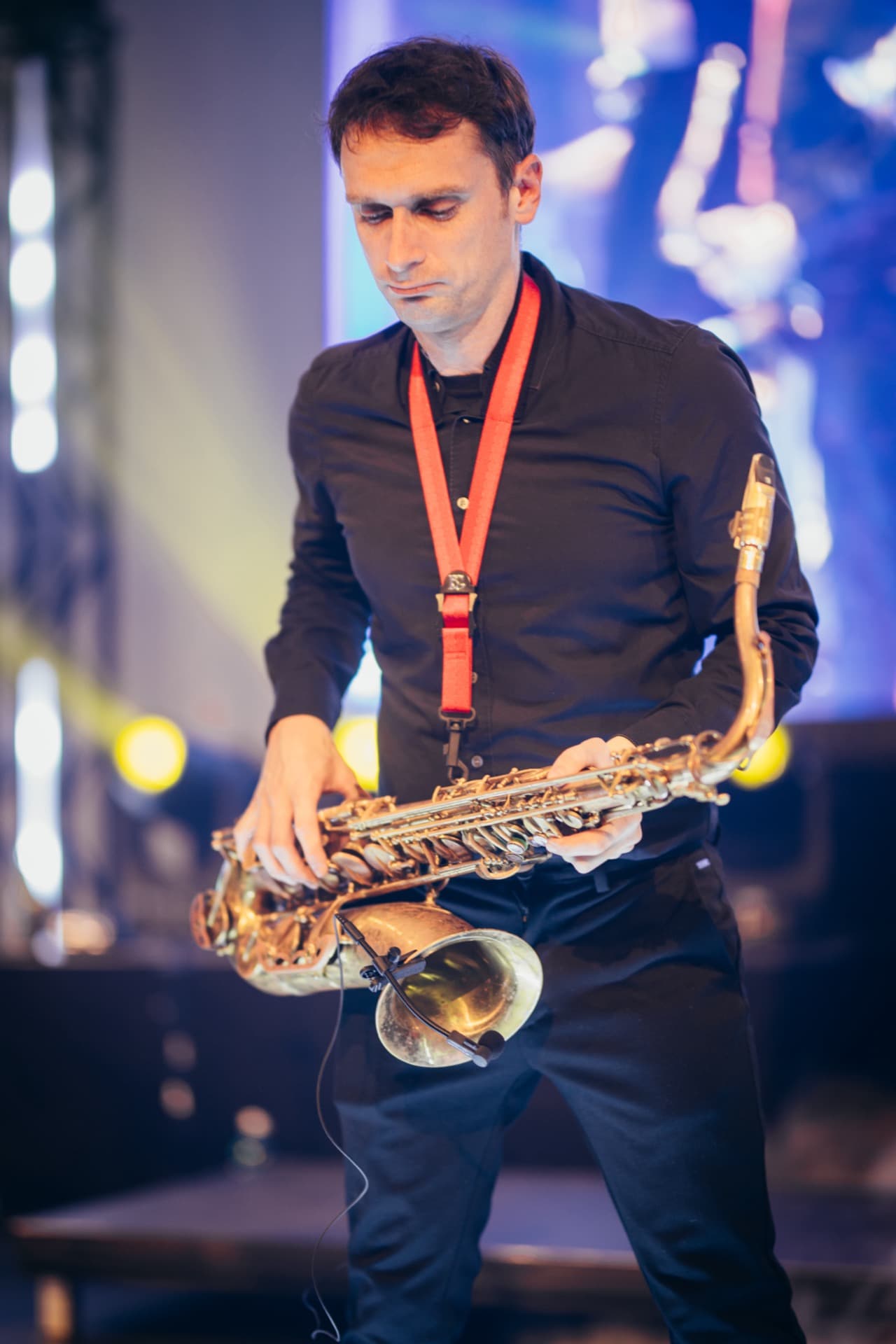 Saxophonist blickt auf sein Instrument, warme goldene Töne
