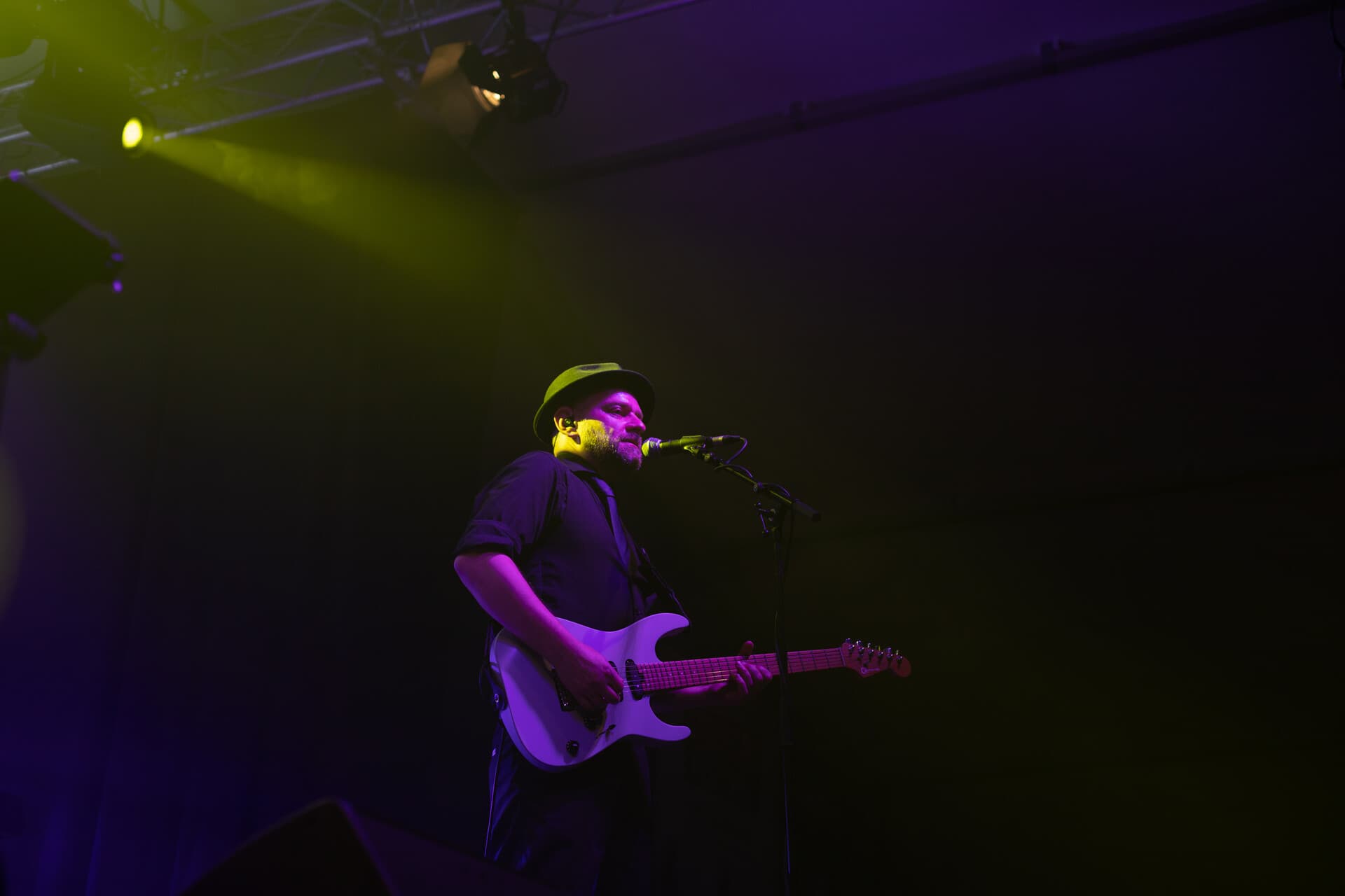 Gitarrist solo in lila-gelbem Licht, Hut-Silhouette