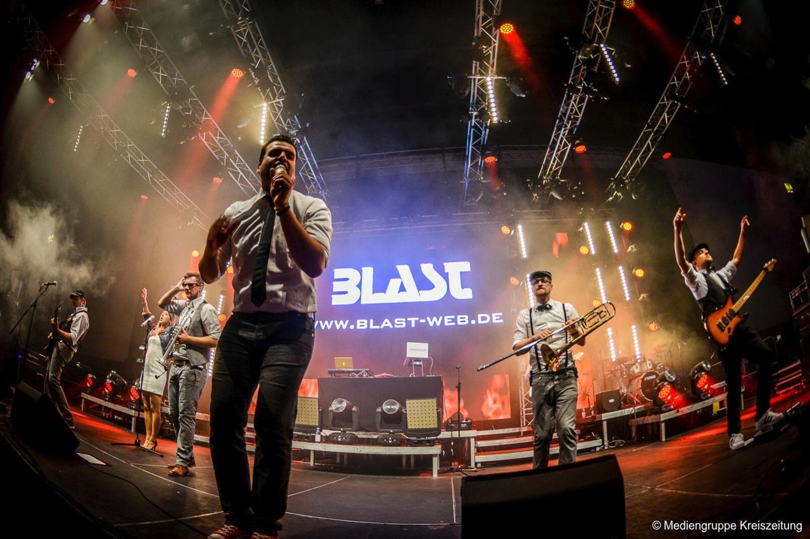 Sänger im Vordergrund mit Band und BLAST Bühnenbranding