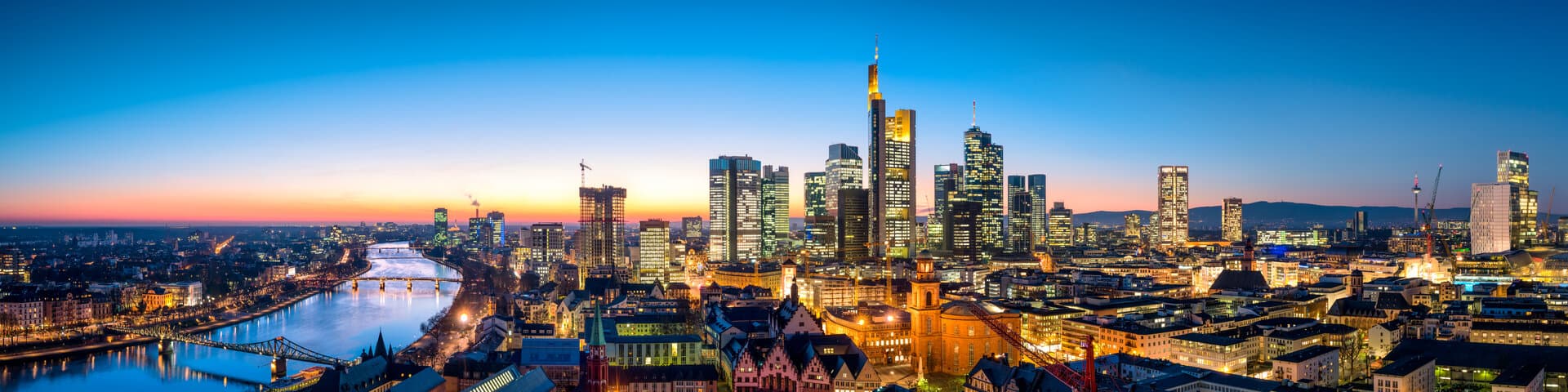 Frankfurter Skyline mit Bankenviertel und Main am Abend